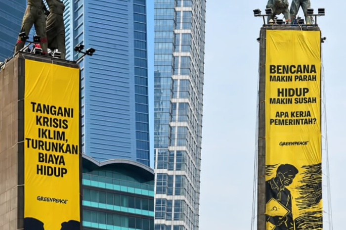 aktivis Greenpeace membentangkan spanduk di Monumen Selamat Datang, Bundaran HI.